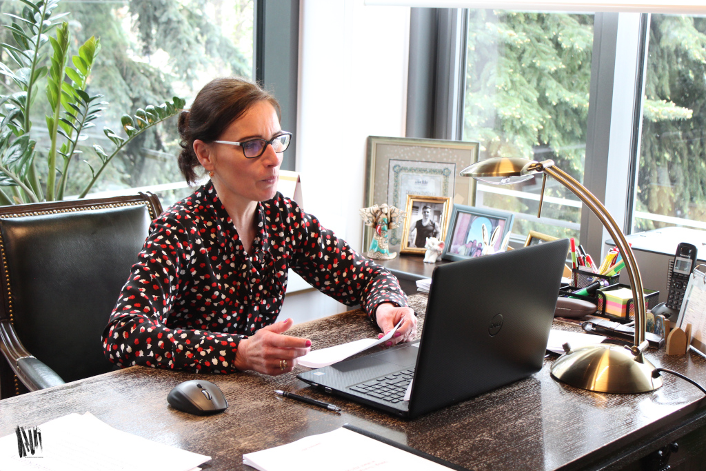 Zdjęcie przedstawia siedzącą kobietę (dyrektor Biblioteki w Jaworznie) spoglądającą na ekran laptopa leżącego na biurku.