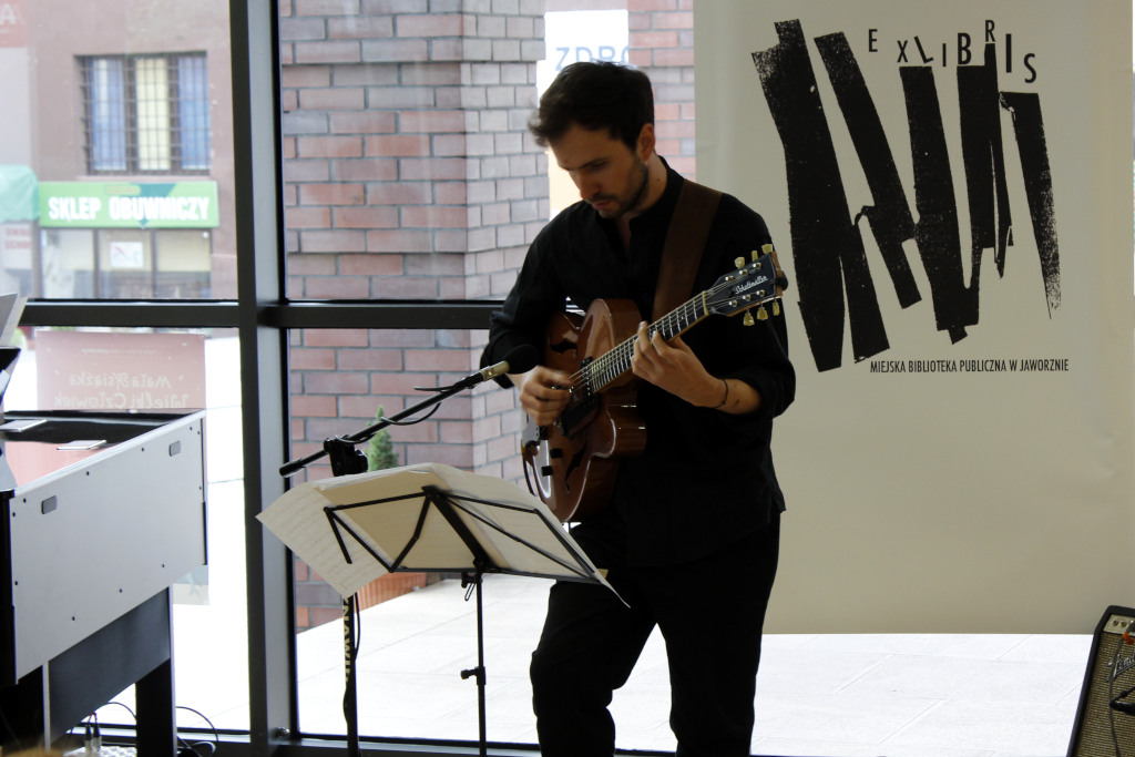 Koncert w holu Biblioteki Głównej na gitarze elektrycznej gra Szymon Mika. 
