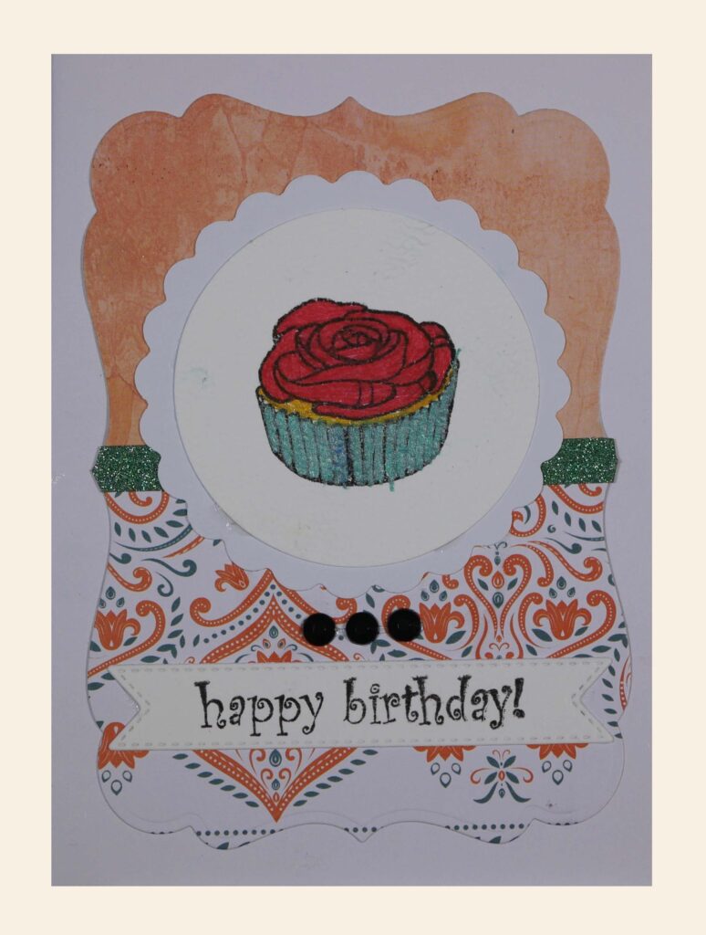Ozdobna kartka. W centralnym miejscu ciastko - babeczka, obok napis: „happy birthday”.